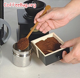 把适量咖啡粉放入咖啡粉杯中，将咖啡粉杯测边轻拍几下，可将表面整平
